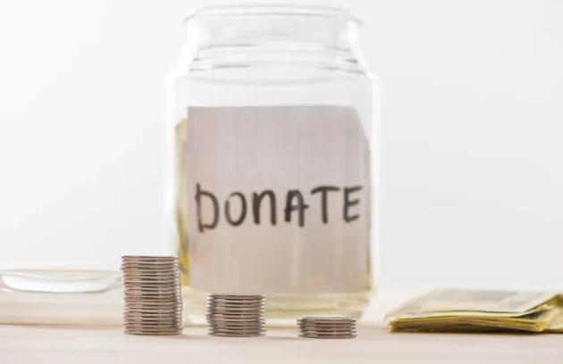 Donation jar with coins and cash, representing one-time and recurring charitable donations.