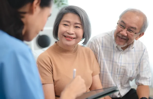 Healthcare professional consulting with a senior Asian couple about future healthcare planning.